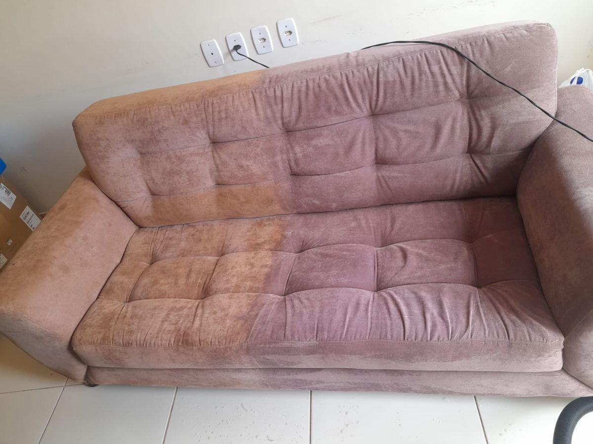 Sofá rosa no meio da higienização: o lado esquerdo ainda sem limpeza, com tom alaranjado, e o lado direito já limpo, com a cor rosa original.